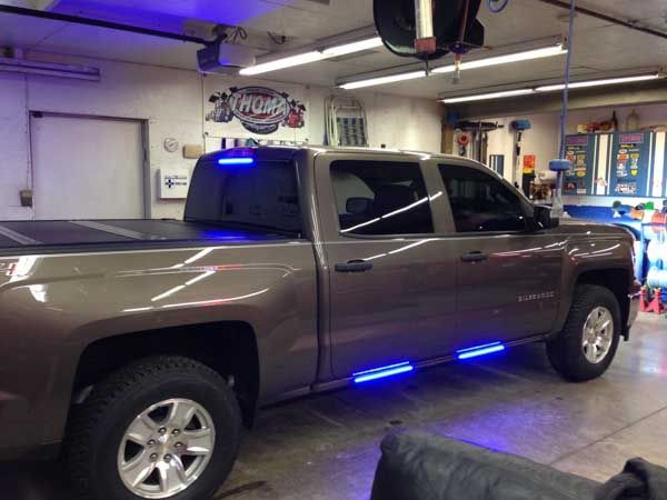 Brown pickup truck with blue LED lights in a garage.