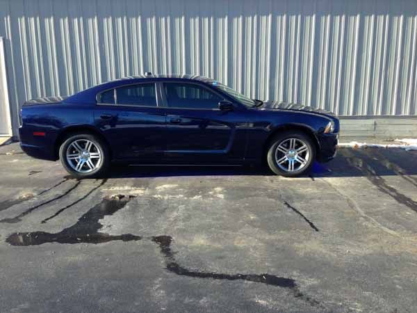 Dark blue Dodge Charger parked in front of a corrugated metal wall.