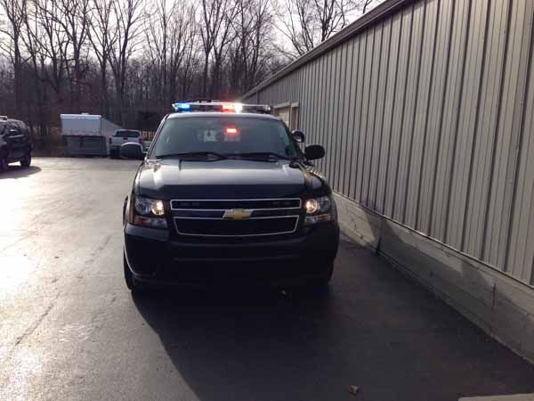 Black police SUV parked next to a building with flashing blue and red lights on.