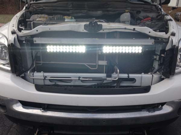 White truck with a bright LED light bar mounted in the front grille.