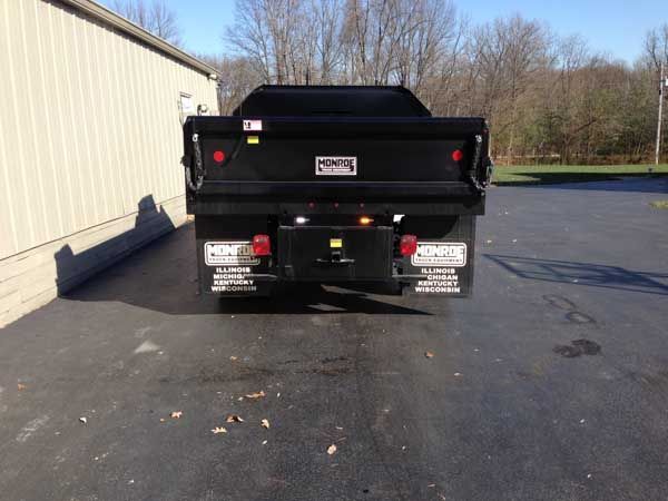 Black dump truck parked near a building.