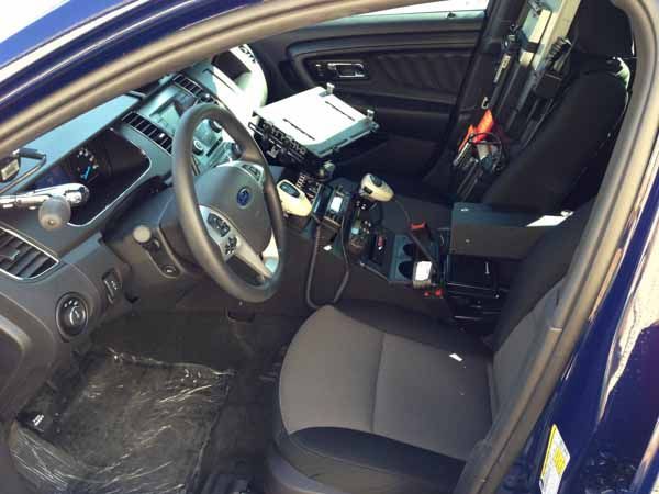 Interior of a dark blue police car. Front seat and dashboard visible. Black and gray details with mounted equipment.