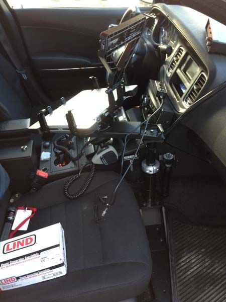 Interior of a police car with installed equipment. Black dashboard and seat with electronic devices and radio control.