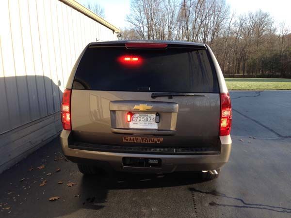 Brown Chevrolet Tahoe with red brake lights illuminated, parked outdoors.