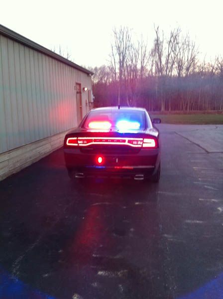 Police car with flashing red and blue lights, parked near a building.