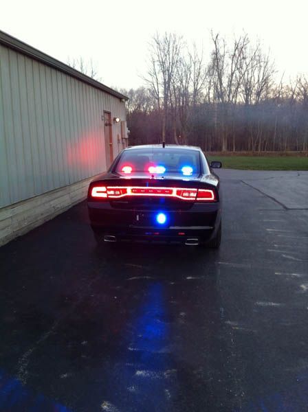 Black car with flashing red and blue lights, parked near a building.
