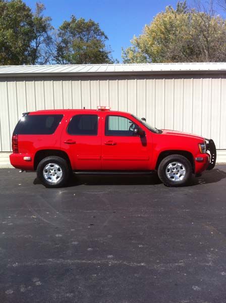 Red SUV parked in front of a white building. The vehicle has chrome wheels and a bull bar.