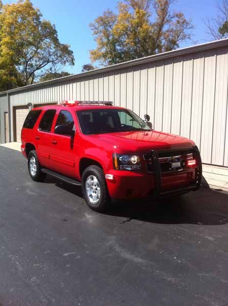 Red SUV fire vehicle parked in front of a building with overhead door.