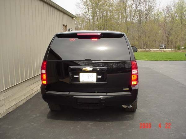 Black Chevrolet Tahoe SUV parked outside a building, license plate visible.
