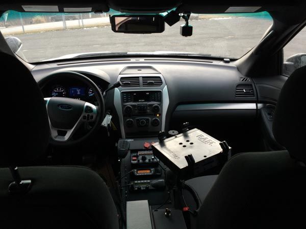 Interior of a police car with dashboard, equipment, and driver's seat.