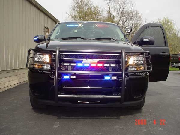 Black police SUV with emergency lights flashing, open driver-side door.