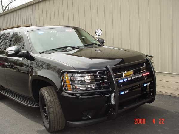 Black police SUV with a push bar and emergency lights. Parked in front of a building.