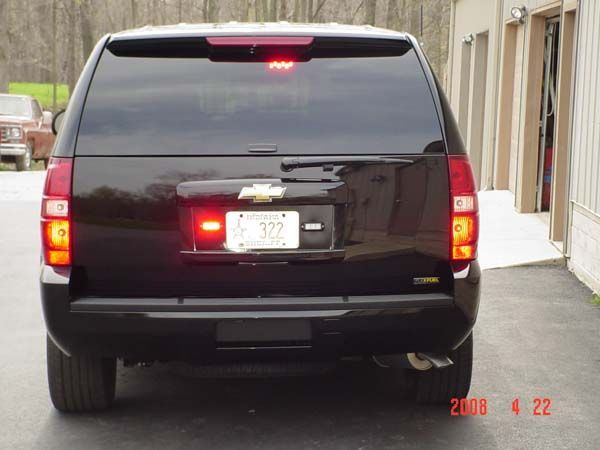 Rear view of a black SUV with illuminated brake lights. A Chevrolet emblem is visible above the license plate.