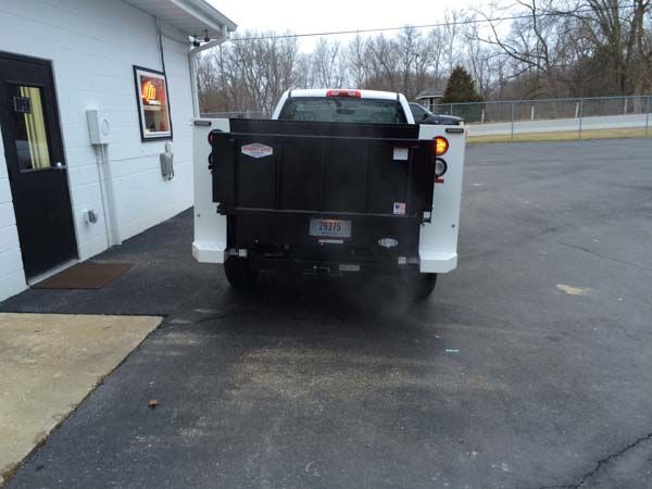 White pickup truck backing up near a building, turn signal on.
