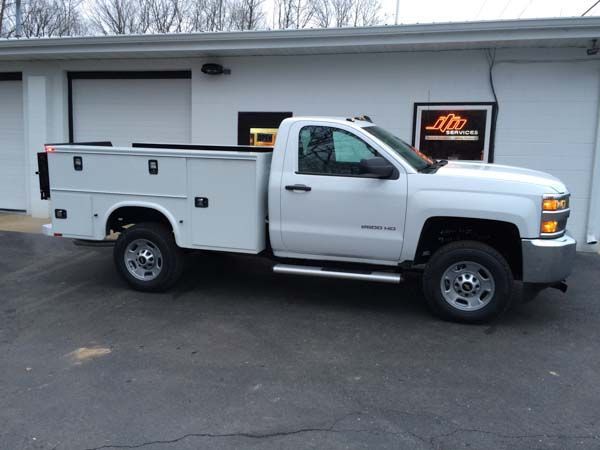 White work truck with toolboxes parked in front of a building.