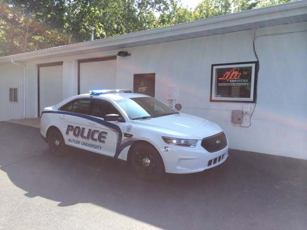Police car parked outside a white building with garage doors. 