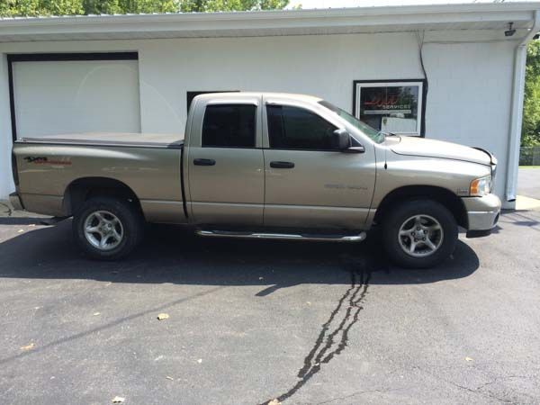 Tan Dodge Ram pickup truck parked in front of a white building with black windows and a closed garage door.