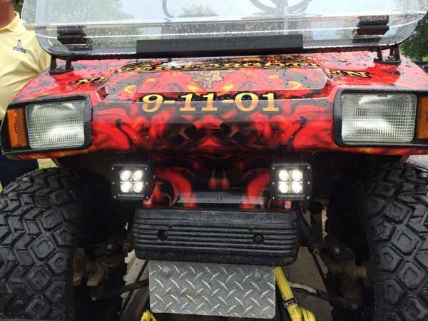 Golf cart with 9-11-01 graphic and flames, two square lights, and large tires.
