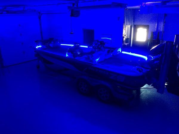 Boat in a dimly lit garage, illuminated by blue lights.