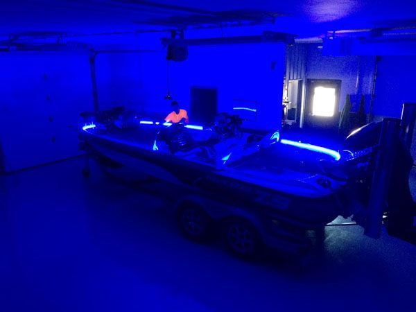 A boat inside a building is illuminated by blue lights. A person is visible inside the boat.