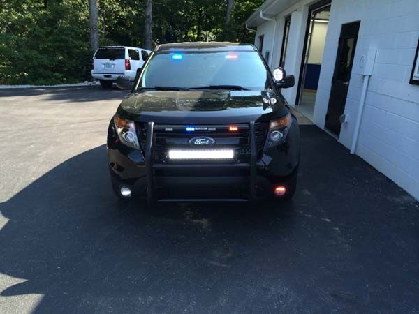 Black police SUV with emergency lights parked in front of a building.