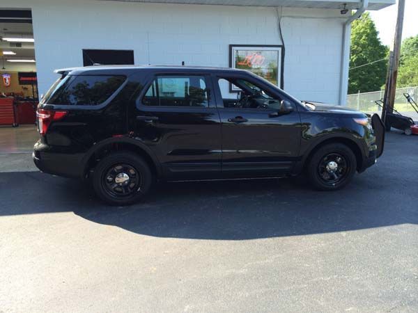 Black police SUV parked in front of a building with a window; sunny day.