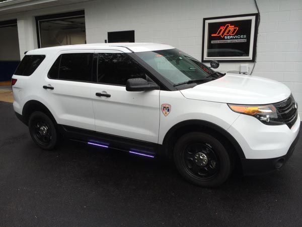 White police SUV with black accents and side lights parked in front of a building.