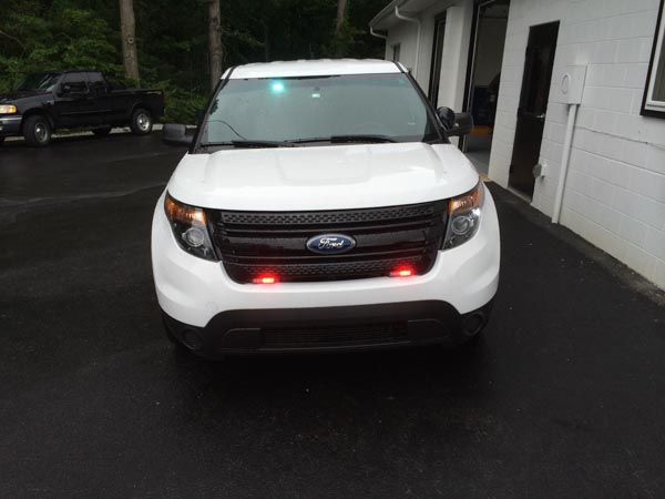 White Ford Explorer police vehicle with flashing red and green lights.