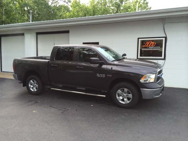 Dark gray Ram pickup truck parked outside a white building with garage doors.