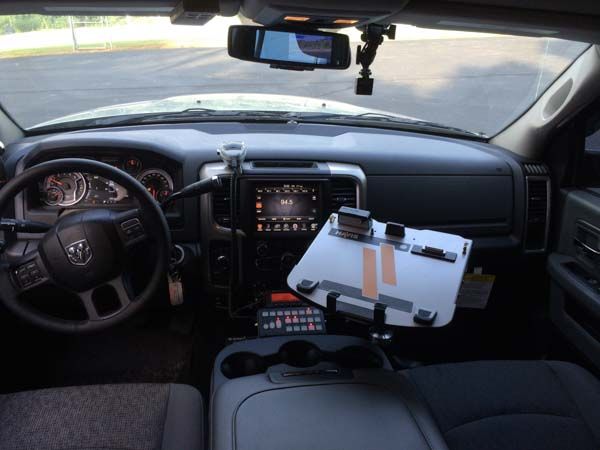 Interior of a vehicle dashboard, including a steering wheel, center console, and a mounted tablet holder.