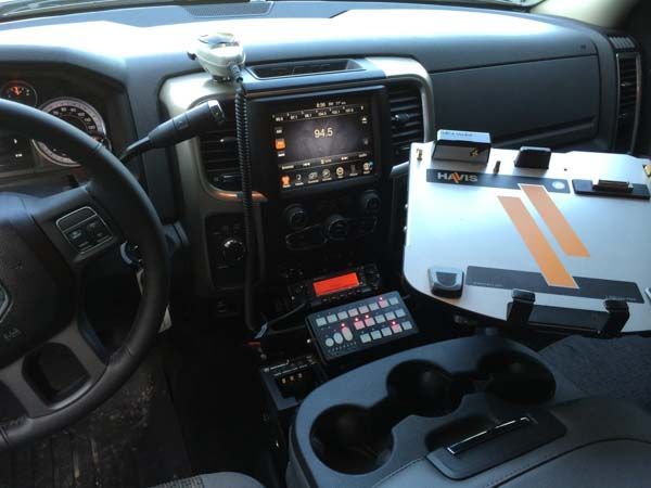 Interior of an emergency vehicle, showing the dashboard with radio, lights, and a work surface.