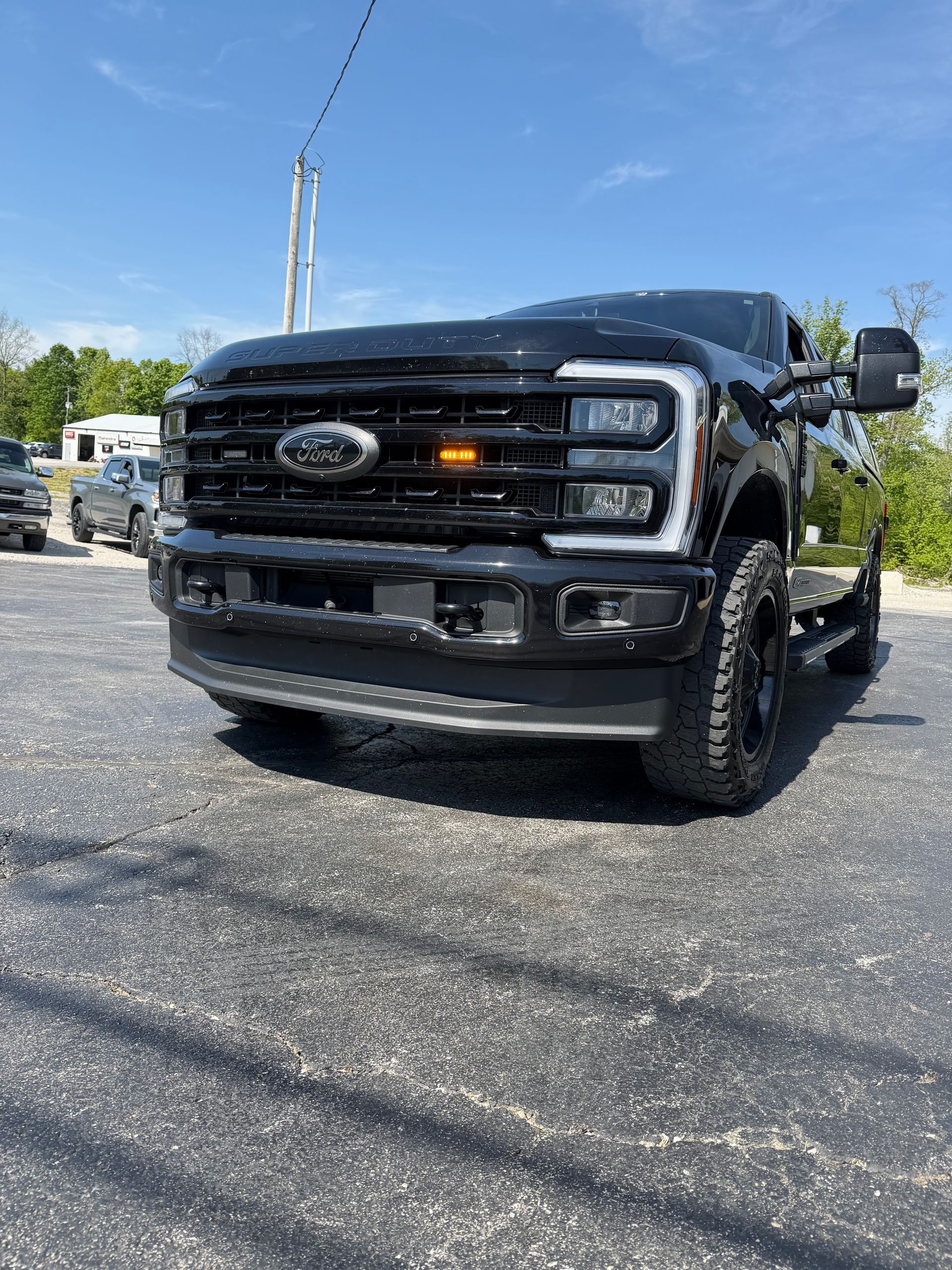 Black Ford pickup truck parked on a sunny paved lot under a blue sky