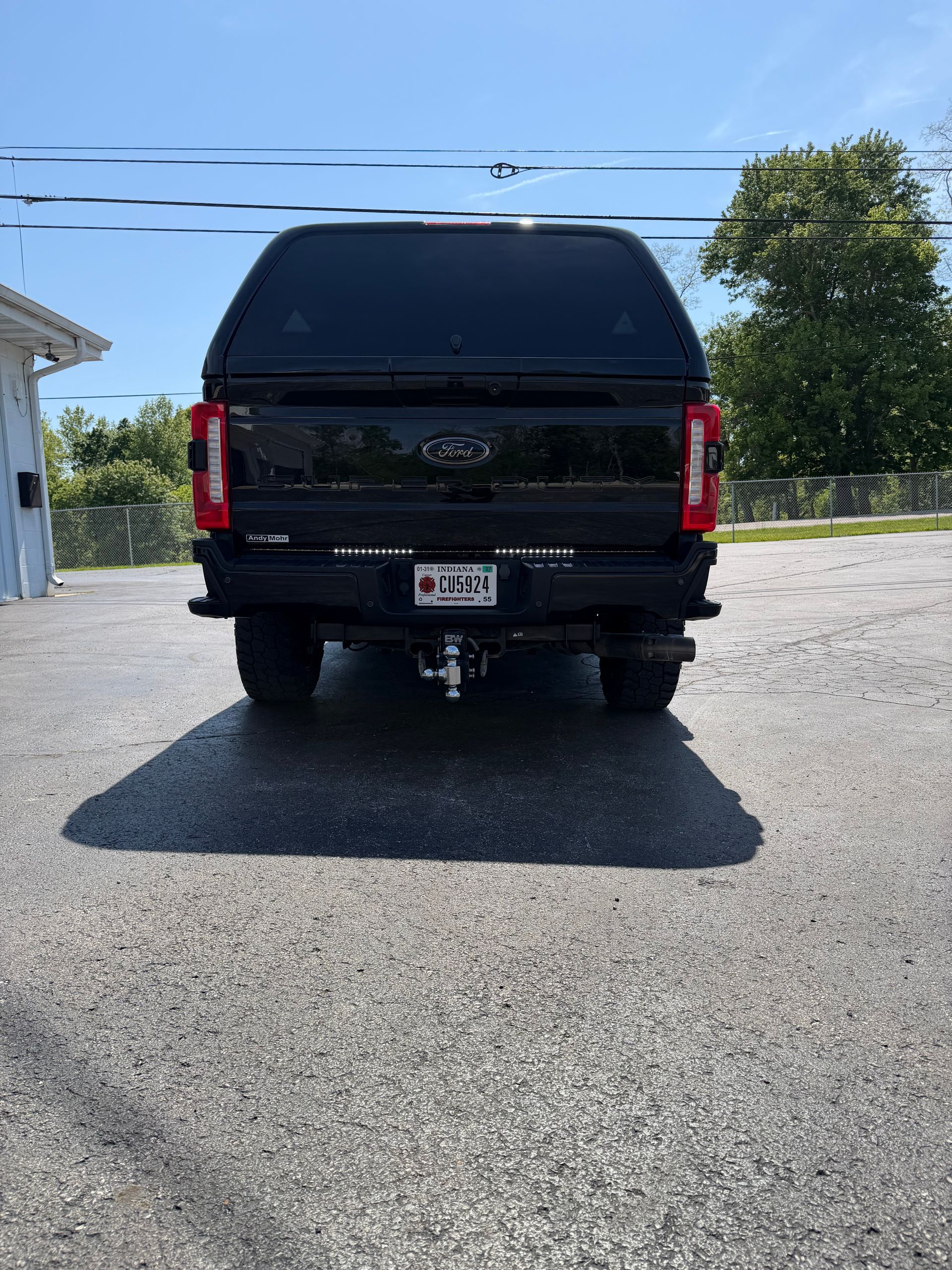 Black pickup truck parked on a sunny driveway, rear view.