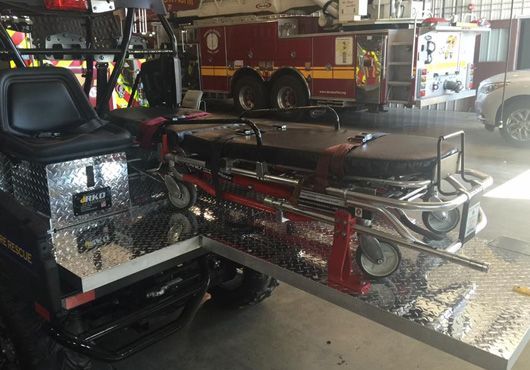 Ambulance stretcher extended from utility vehicle in a fire station.