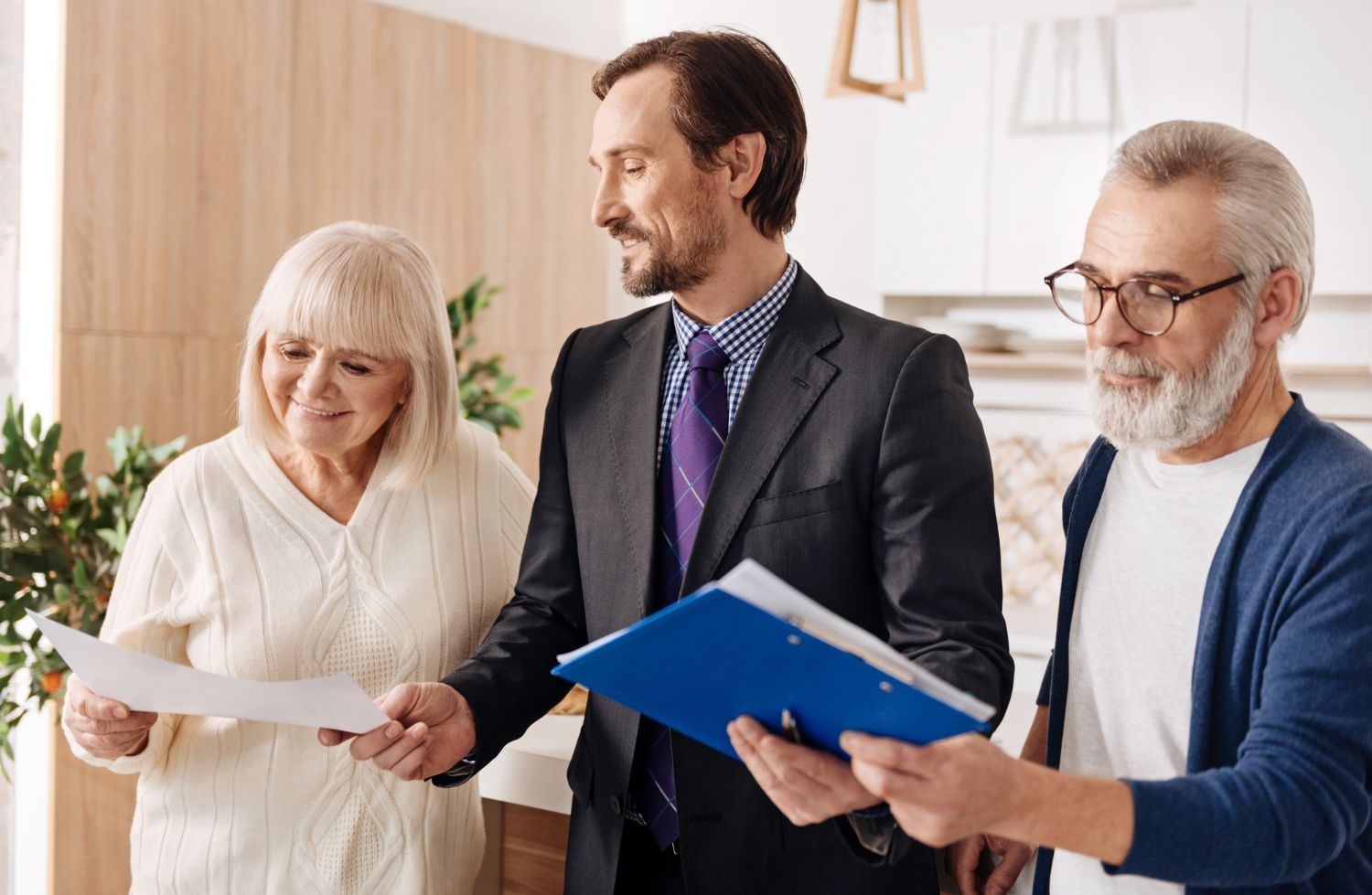 Three people reviewing documents together in a bright office