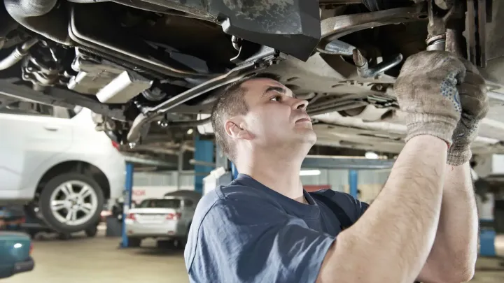 A man is working under a car in a garage. A man is working under a car in a garage.