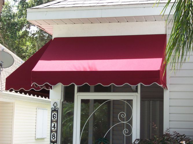 Maroon awning over a white-framed door with decorative wrought iron, set on a white porch.
