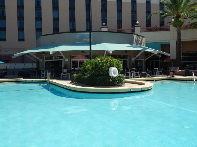 Blue awning over poolside seating area.