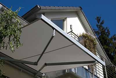 A white awning extends from a balcony on a building, blue sky above.