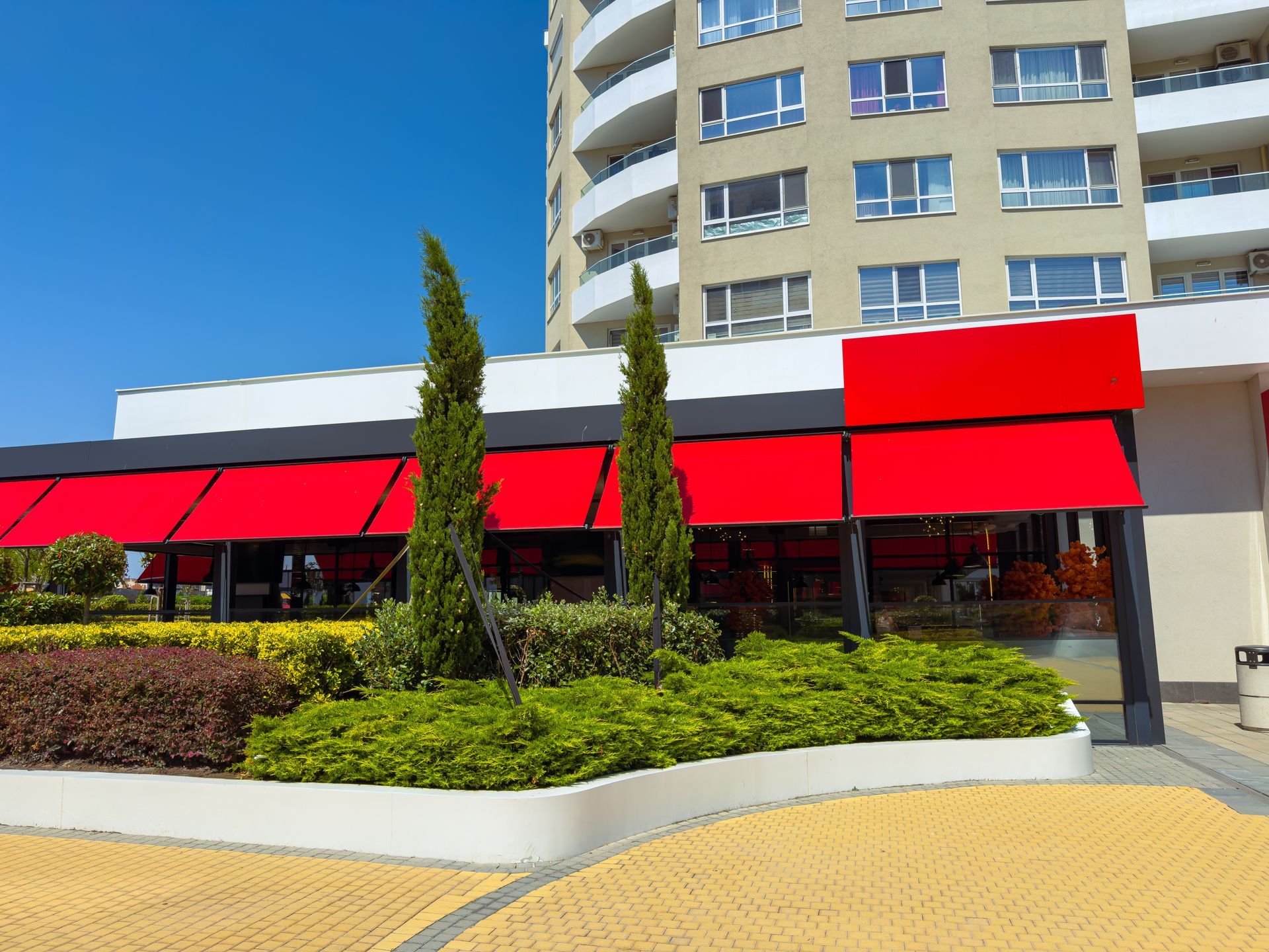 Bright red awnings cover a building at a busy location in the city during a sunny day.