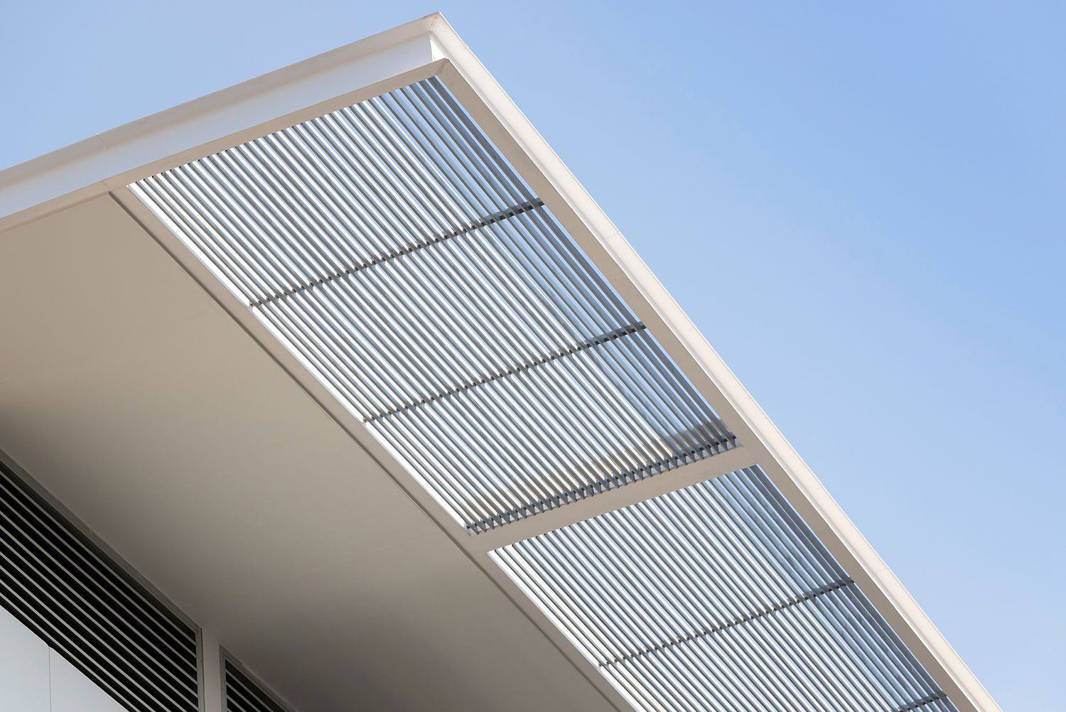 Modern house with steel exterior metal awnings providing shade under a clear blue sky.