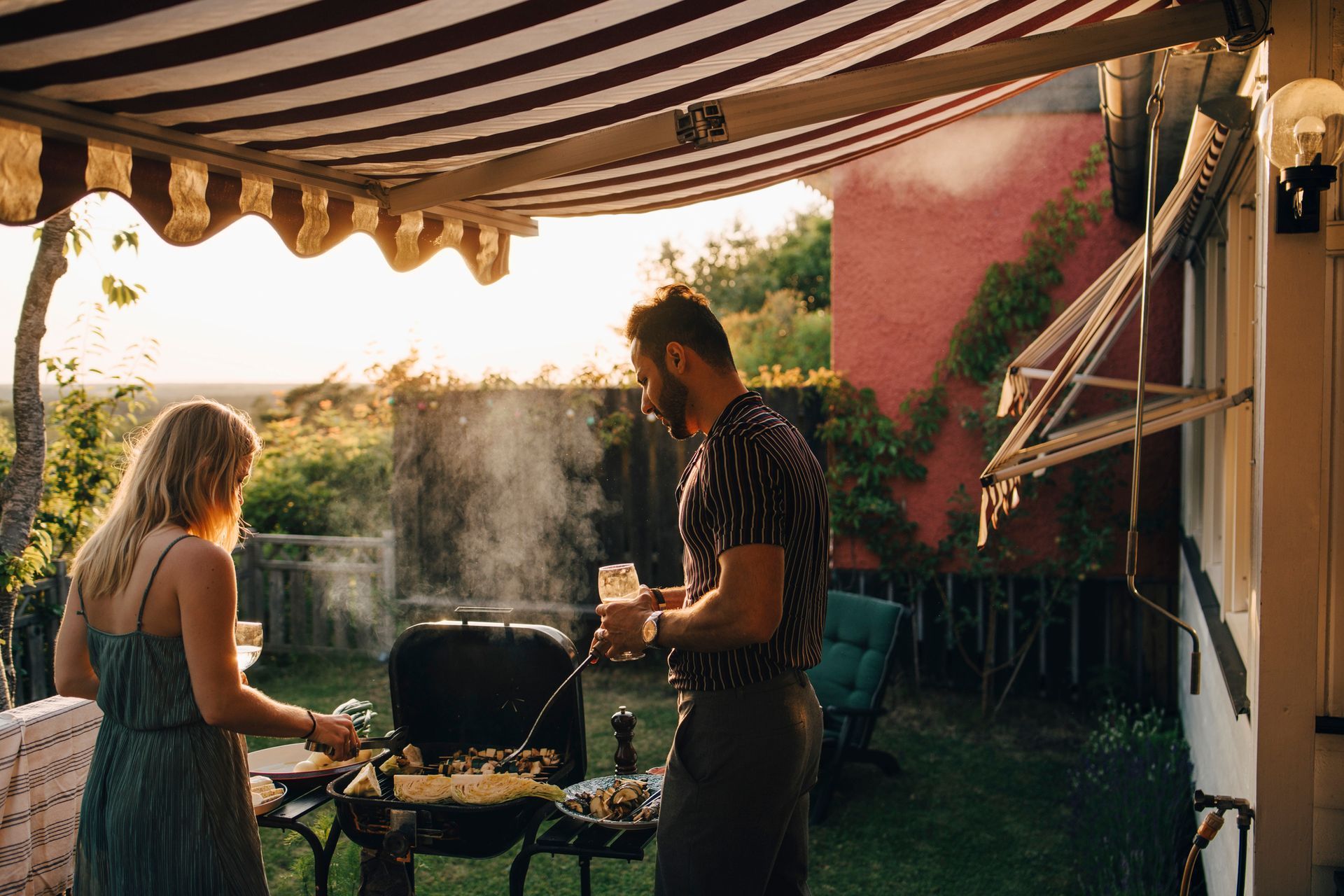 A couple is grilling food in the yard.