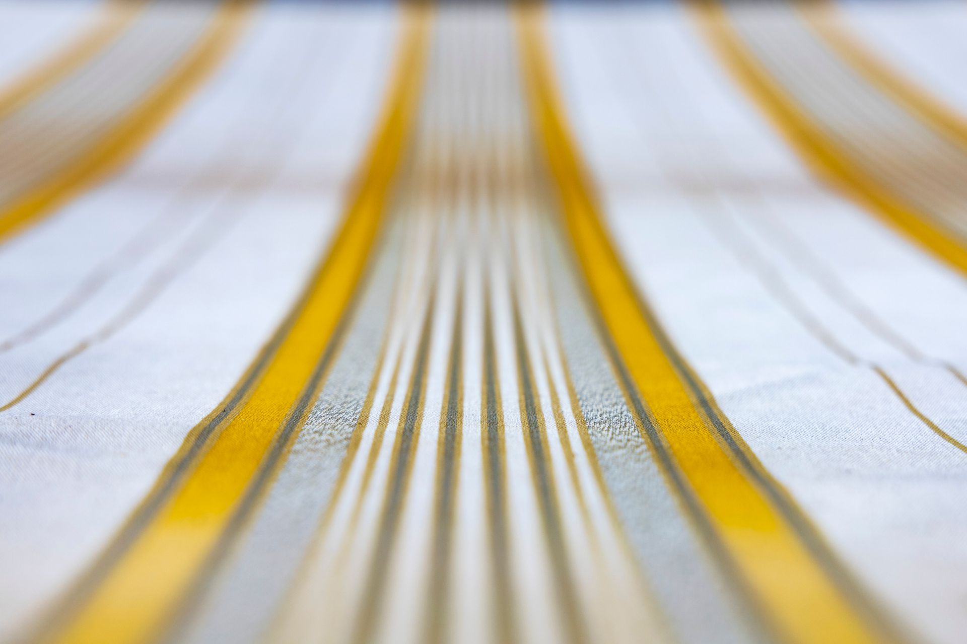 Yellow and white striped fabric, viewed at a shallow angle with a blurred background.