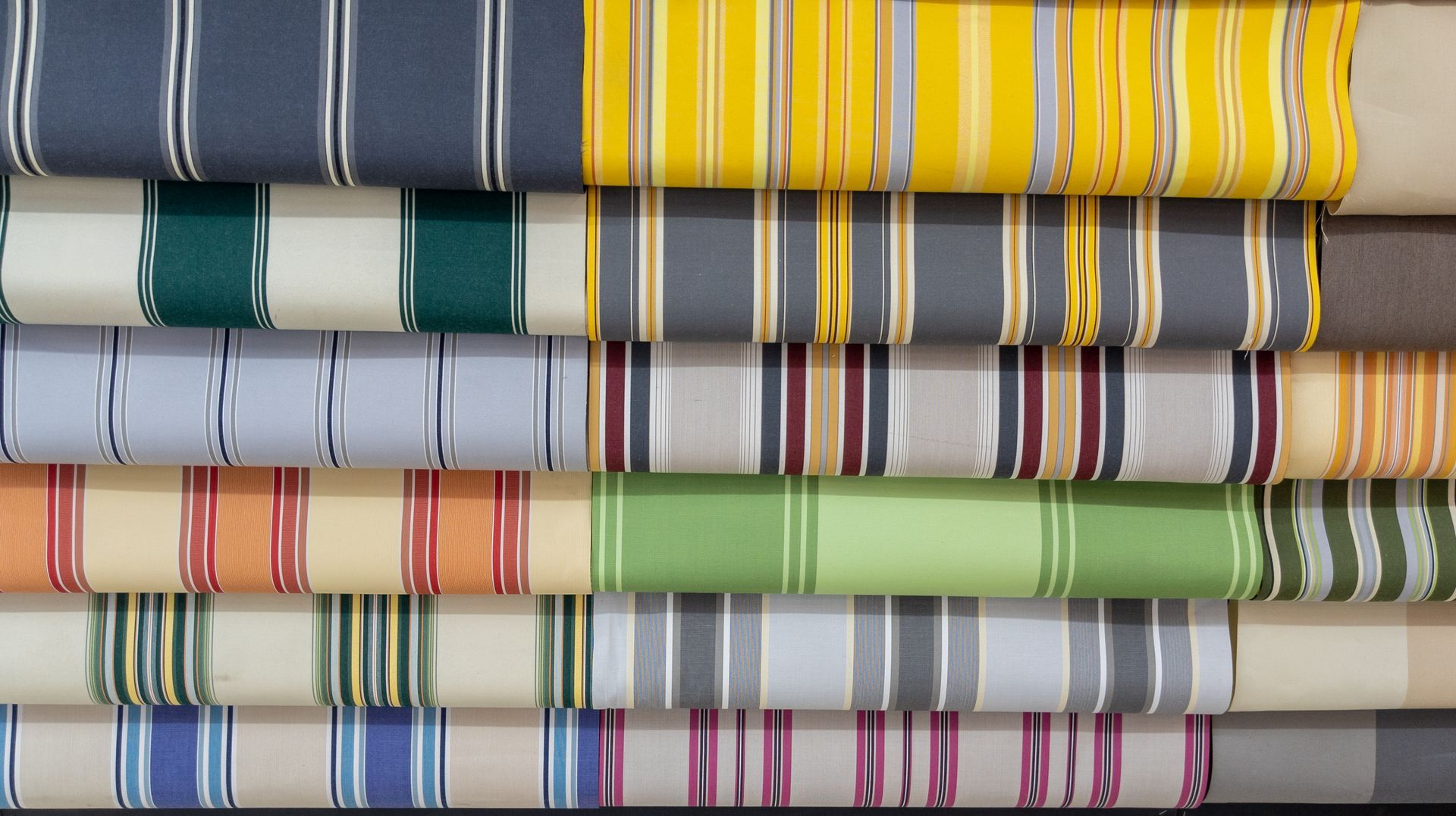 Striped awning fabrics in various colors, including yellow, green, and gray.