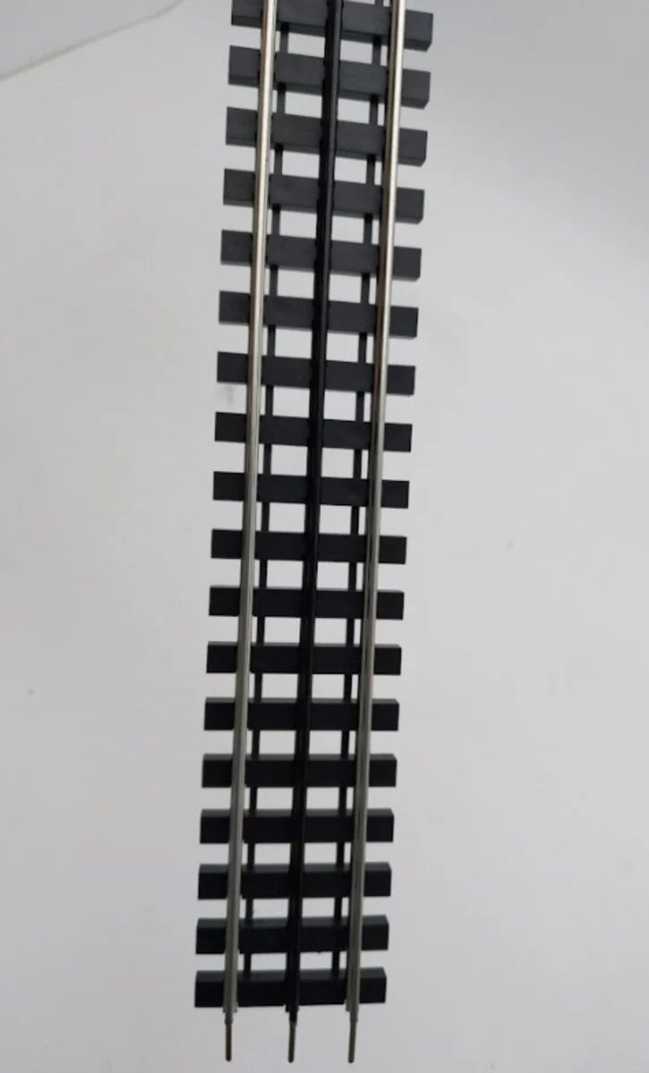 Close-up of a black model train track on a light background.