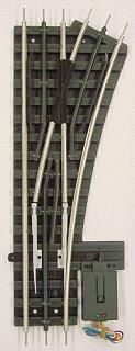 Curved model railroad track with a gray switch machine and wiring on a white background