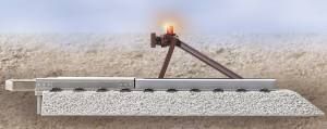 Damaged railway track with a burning lever or device beside the rail on a snowy ground