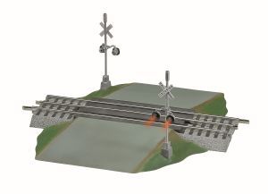 Railroad crossing with lowered gates over a road at dusk, next to a small grassy embankment.