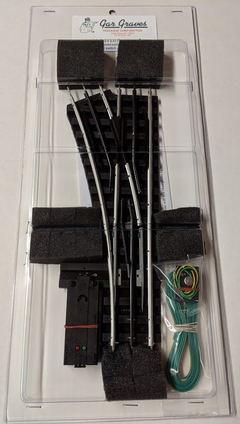 Clear plastic packaging with black rail pieces and a green cable inside a kit.