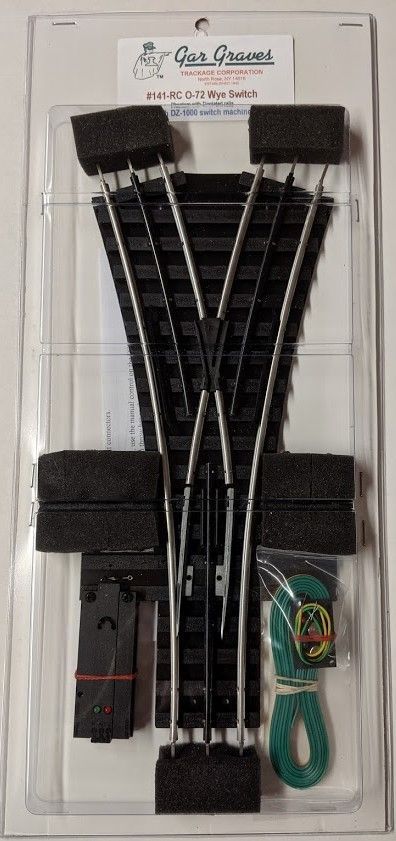 Blister-packaged black train track kit with curved rails and green-handled accessory on white backing